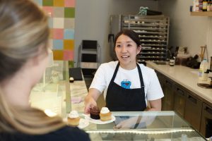 Small business shop owner serving a customer in her cup cake shop.