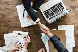 Two people shaking hands across a table