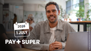 A business owner smiling beside his computer with the message 'PayDay Super is from 1 July'